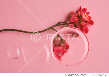 Three drops of cosmetic transparent gel on a pink background. The texture of the serum. 105715757