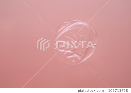 Drop of cosmetic transparent gel on a pink background. The texture of the serum, heir gel or hyaluronic booster. 105715758