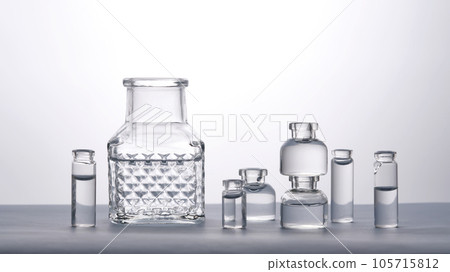 Different bottles of water on a light background. It can fit the theme of cosmetics, glass and freshness. Different bottles of water on a light background. It can fit the theme of cosmetics, glass and freshness. 105715812