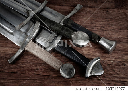 Medieval swords on wooden backgrond. 105716077