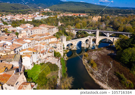 View from drone of Besalu with arched bridge over Fluvia river 105716384