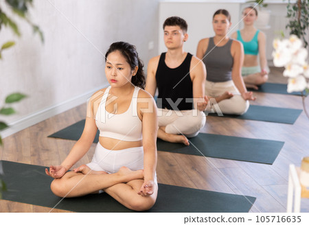 Group of young people meditating in a lotus pose. Group of young people meditating in a lotus pose. 105716635