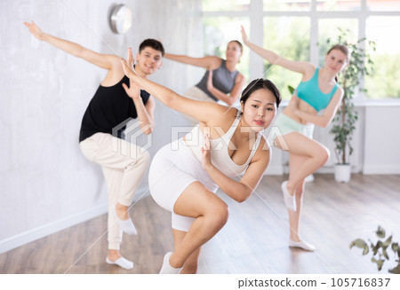 Positive young woman practicing dance positions during workout session 105716837