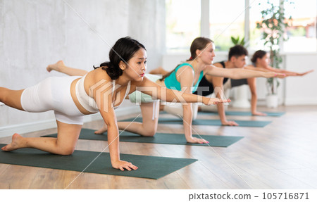 Young man and women yoga showing others plank pose in gym Young man and women yoga showing others plank pose in gym 105716871