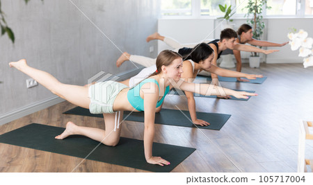 Slim young girl training balancing table pose of yoga on black mat Slim young girl training balancing table pose of yoga on black mat 105717004