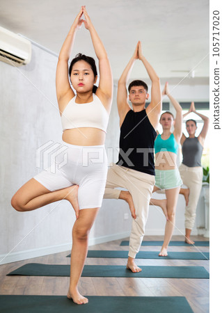 Young Asian girl performs stand Tree asana, Vrikshasana Young Asian girl performs stand Tree asana, Vrikshasana 105717020