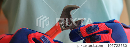 Close up of repairman gloved hands with metal wrench. Close up of repairman gloved hands with metal wrench. 105722380