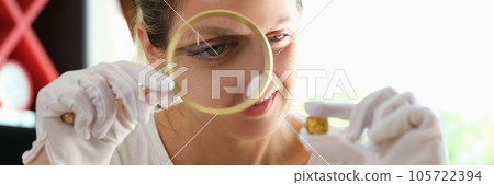 Woman numismatist looking through magnifying glass at gold coin close up. Woman numismatist looking through magnifying glass at gold coin close up. 105722394