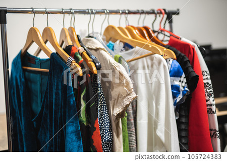 Many different colored women's clothes on hangers in a store 105724383