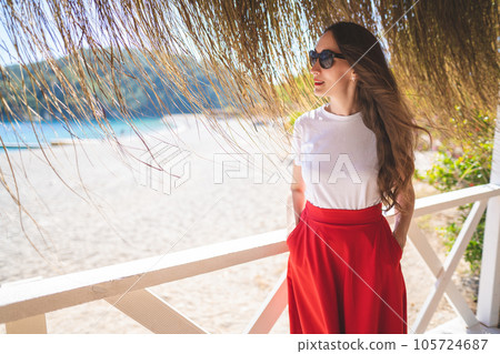 beautiful girl in a red skirt and sunglasses in the summer on a terrace on the shore of the sea beautiful girl in a red skirt and sunglasses in the summer on a terrace on the shore of the sea 105724687
