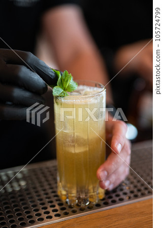 the bartender prepares a beautiful alcoholic cocktail at the bar counter 105724799