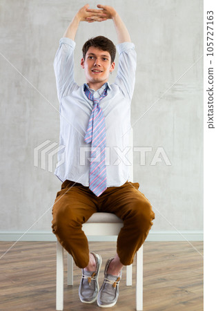 Young guy office worker doing exercises on chair 105727163