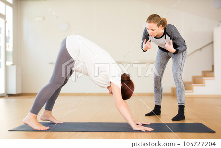 Pregnant woman practices yoga with an instructor 105727204