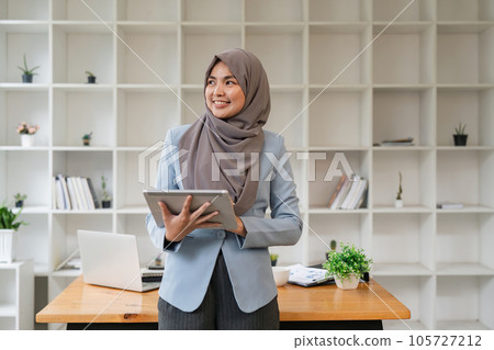 Happy muslim business women in hijab at work. smiling arab woman holding tablet 105727212