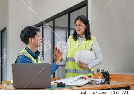 Construction engineer with blueprint making high five while standing on construction site. Home building concept 105727213