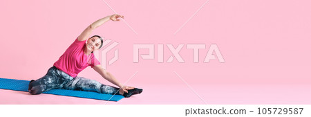 Mature woman in black sportswear training, doing stretching against pink studio background. Banner Mature woman in black sportswear training, doing stretching against pink studio background. Banner 105729587