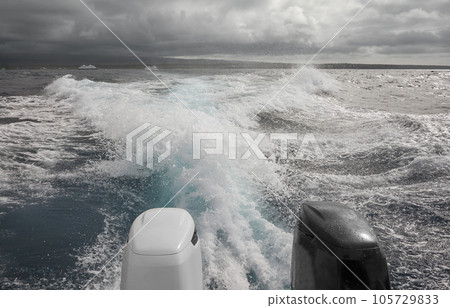 Powerful outboard motors of a speedboat fleeing a storm, selective focus. Powerful outboard motors of a speedboat fleeing a storm, selective focus. 105729833