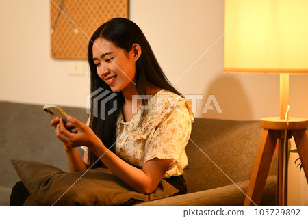 Carefree young woman texting message or browsing social networks on smartphone 105729892