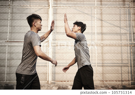 two young asian athletes giving hi-five celebrating success 105731314