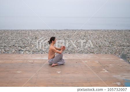 Caucasian man with naked torso practicing wushu on the seashore. Caucasian man with naked torso practicing wushu on the seashore. 105732007