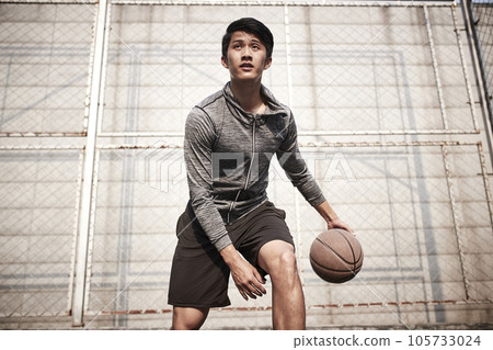 young asian male basketball player practice ball handling skills on outdoor court young asian male basketball player practice ball handling skills on outdoor court 105733024