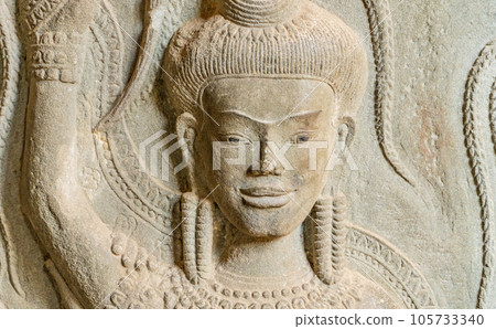 Wall carving with womans dancers apsara. Ancient ruins Angkor Wat temple - famous Cambodian landmark. Siem Reap, Cambodia. Wall carving with womans dancers apsara. Ancient ruins Angkor Wat temple - famous Cambodian landmark. Siem Reap, Cambodia. 105733340