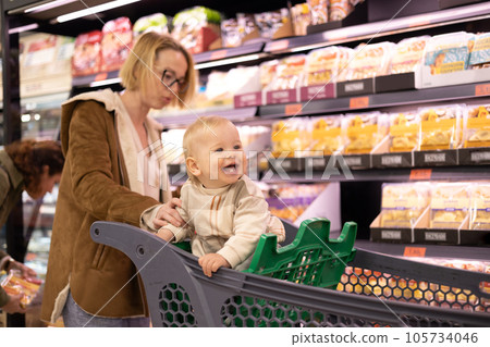 Caucasian mother shopping with her infant baby boy child choosing products in department of supermarket grocery store Caucasian mother shopping with her infant baby boy child choosing products in department of supermarket grocery store 105734046