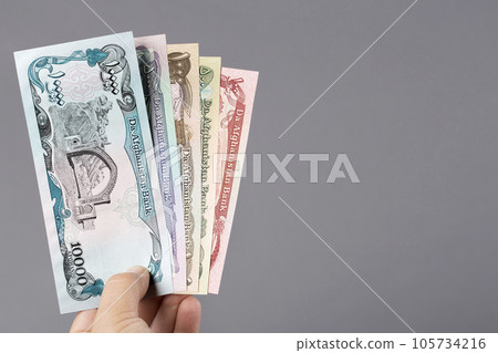Afghan money in the hand on a gray background Afghan money in the hand on a gray background 105734216