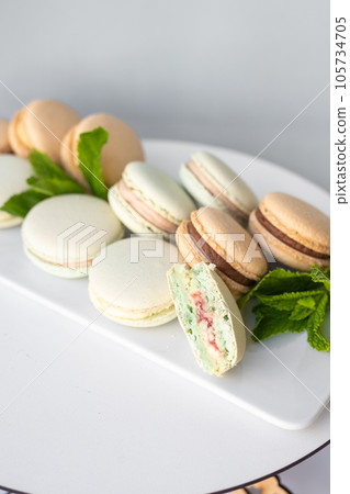Macaroons of different colors with sprigs of mint on a white background. Macaroons of different colors with sprigs of mint on a white background. 105734705