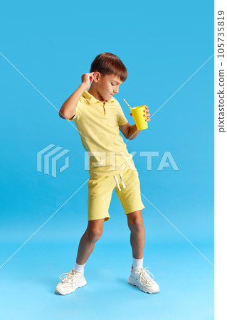 Full-length of cheerful little boy, child in casual clothes posing, dancing against blue studio background Full-length of cheerful little boy, child in casual clothes posing, dancing against blue studio background 105735819