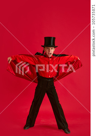 Emotive little boy, child wearing costume for school halloween party, posing against red studio background Emotive little boy, child wearing costume for school halloween party, posing against red studio background 105735871