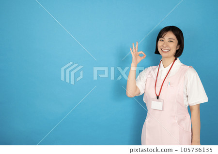 A caregiver woman giving an OK sign on a blue back 105736135