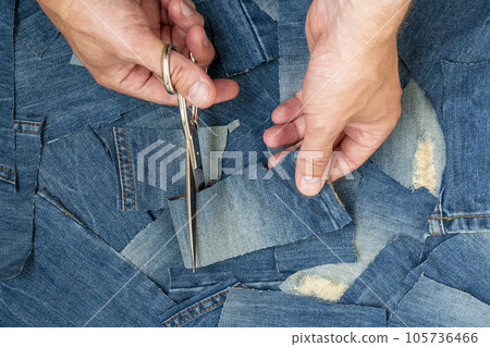 Tailor cutting blue jeans in sewing studio.Circular economy. Tailor cutting blue jeans in sewing studio.Circular economy. 105736466