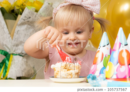 Two-year-old blonde girl eating birthday cake on her birthday. Two-year-old blonde girl eating birthday cake on her birthday. 105737567