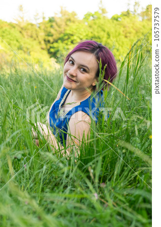 Happy young woman lying in grass in nature in summer Happy young woman lying in grass in nature in summer 105737579