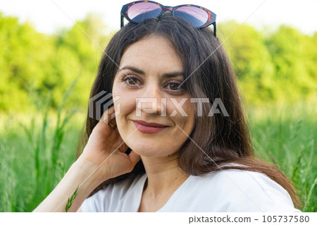 Portrait of a 35-year-old brunette woman looking at the camera smiling in nature. Portrait of a 35-year-old brunette woman looking at the camera smiling in nature. 105737580