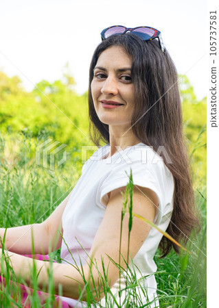 Portrait of a 35-year-old brunette woman looking at the camera smiling in nature. Portrait of a 35-year-old brunette woman looking at the camera smiling in nature. 105737581