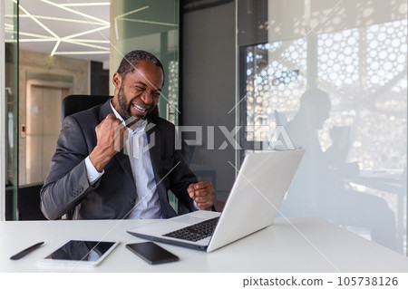 Mature experienced businessman celebrating victory success at workplace, boss inside office happy with financial results achievement received online notification win message, holding hands up. 105738126