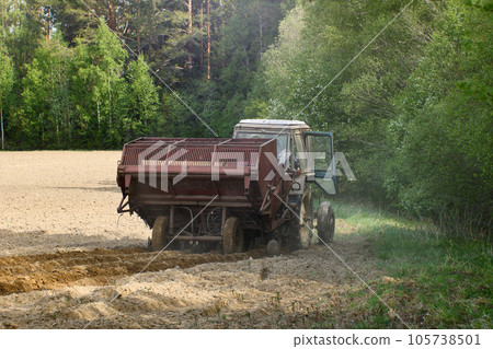 Potato planter is attached to an agricultural tractor for planting potatoes in farmer field. Potato planter is attached to an agricultural tractor for planting potatoes in farmer field. 105738501