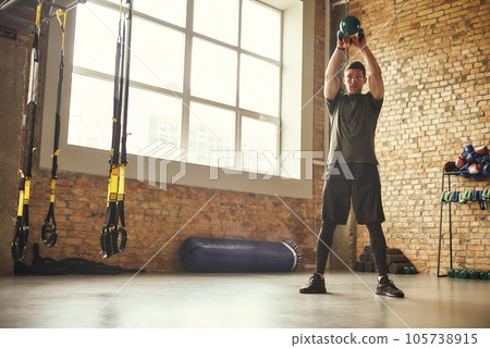Making perfect body. Full-length of strong and handsome man holding big black dumbbell under his head while exercising at gym. Making perfect body. Full-length of strong and handsome man holding big black dumbbell under his head while exercising at gym. 105738915