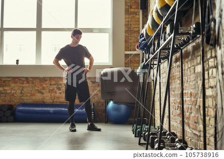 Ready for workout. Confident young man is looking at sport equipment while exercising at gym. Ready for workout. Confident young man is looking at sport equipment while exercising at gym. 105738916