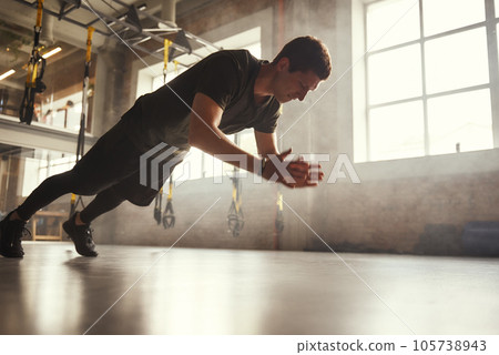 Strength and motivation. Full length of young athletic man in sportswear doing push-up exercises at gym Strength and motivation. Full length of young athletic man in sportswear doing push-up exercises at gym 105738943