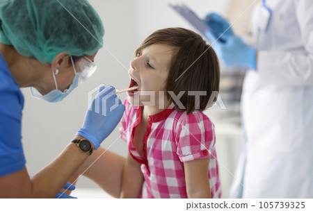 Little girl's throat is examined at doctor's appointment. 105739325