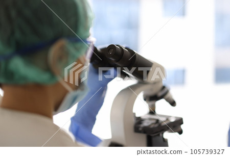 Medical research scientist looks through a microscope. Medical research scientist looks through a microscope. 105739327