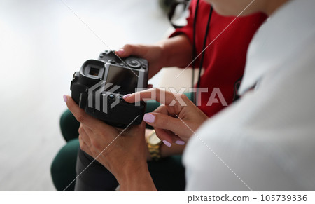 Two women hold camera in their hands 105739336