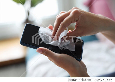 Female hand wipes smartphone with disinfectant napkin from bacteria 105739356