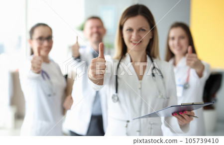 Successful medical team in white coats hold their thumbs up Successful medical team in white coats hold their thumbs up 105739410