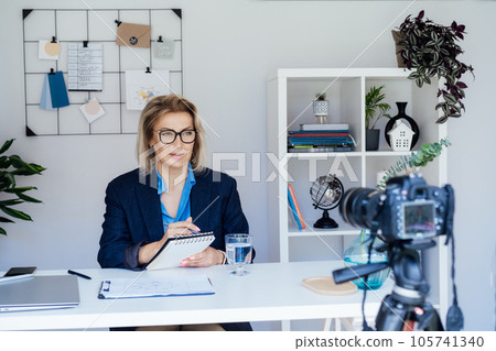 50's confident mature businesswoman, middle-aged experienced senior female professional recording video vlog webinar, online course. Female edtech entrepreneur shares skills, blogger online business. 50's confident mature businesswoman, middle-aged experienced senior female professional recording video vlog webinar, online course. Female edtech entrepreneur shares skills, blogger online business. 105741340