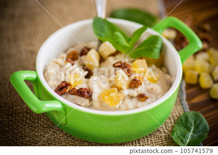 cooked boiled sweet oatmeal with nuts and candied fruits in a bowl 105741579