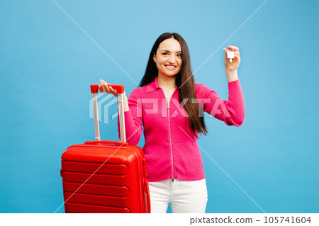 Young woman holding a suitcase showing the keys isolated over blue background 105741604